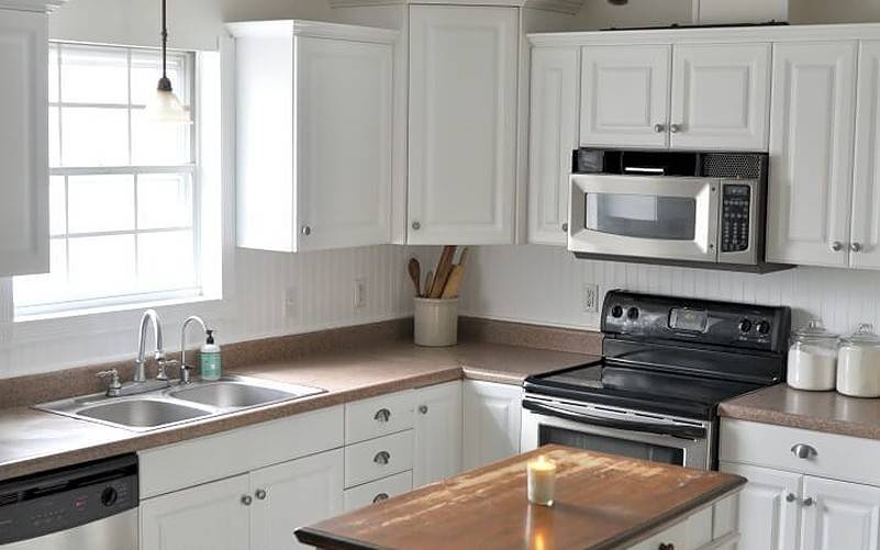 White cabinetry in kitchen with one candle on counter