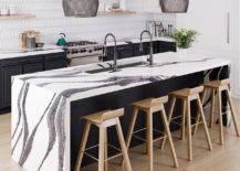 Black and white kitchen counter with sink and wooden chairs