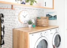 Brown basket and wall clock on top of washer and dryer