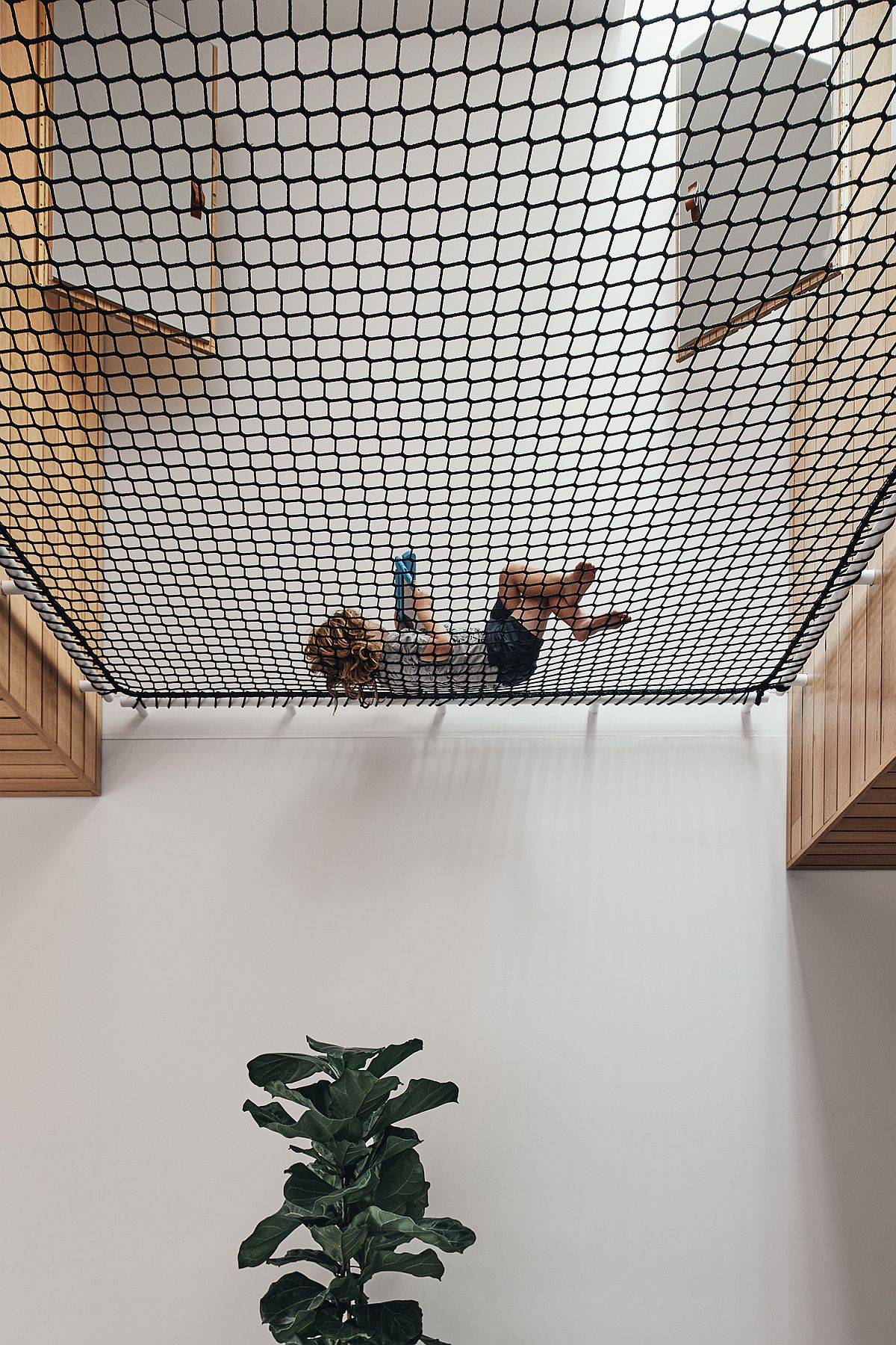 Central void of the home with a net on the upper level that helps everyone rest and relax