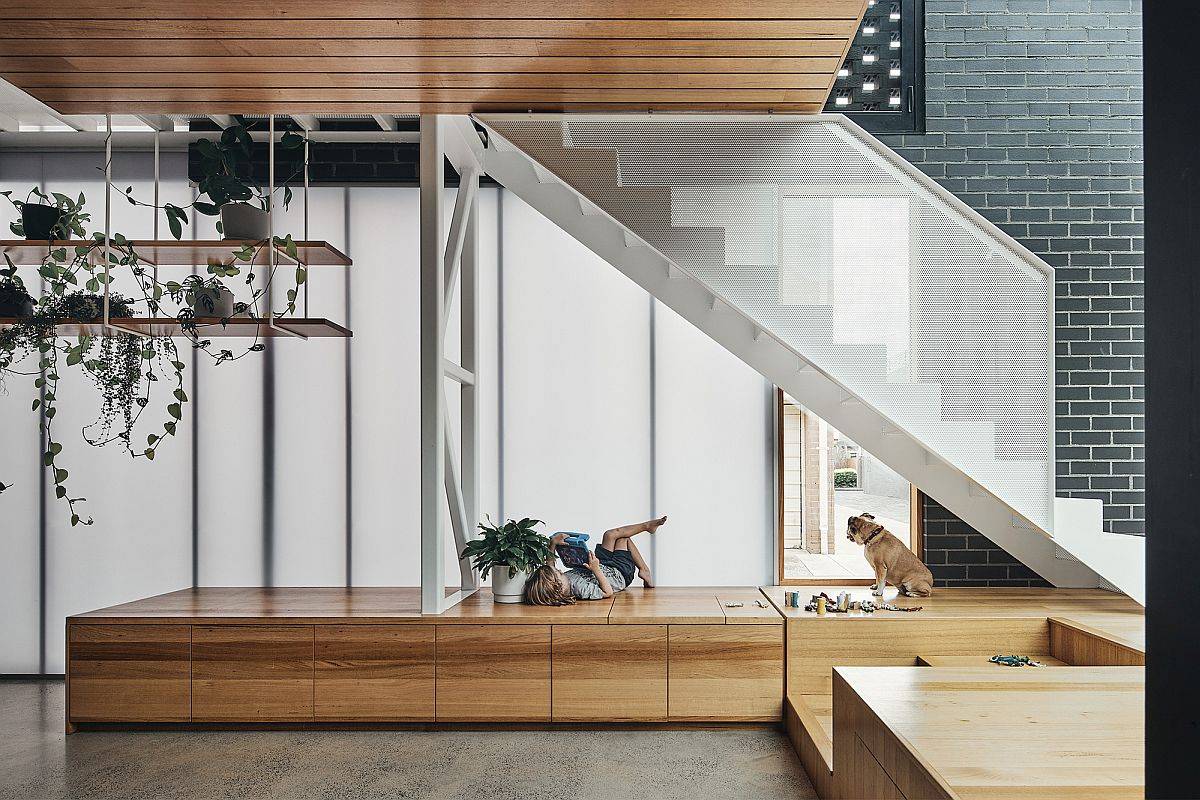 Custom wooden platform under the staircase with wooden storage built-in boxes