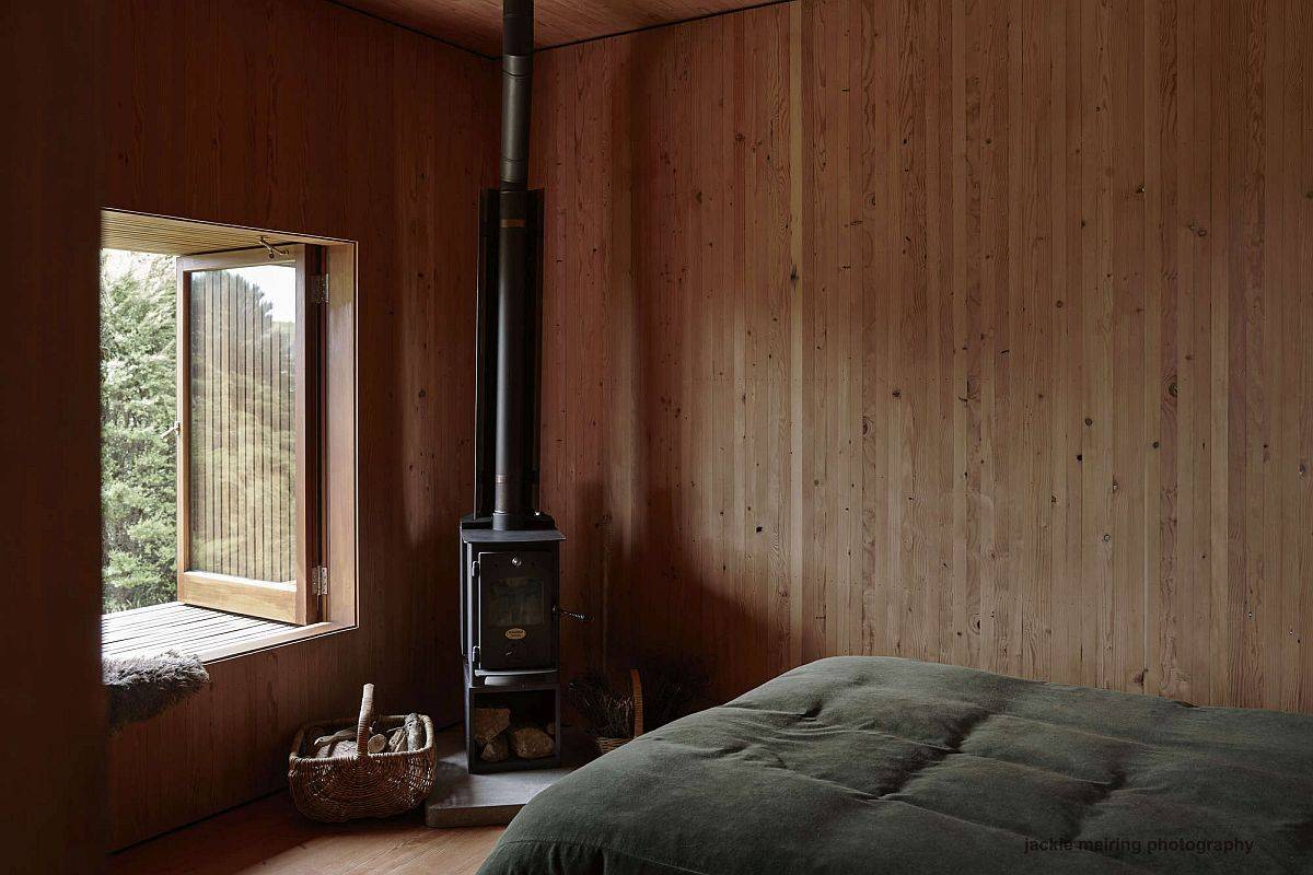 Fireplace in the corner of the bedroom brings warmth to the woodsy modern setting