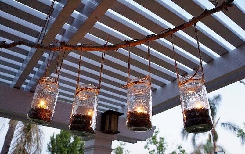 Four mason jars hanging with tea lights hanging from pergola