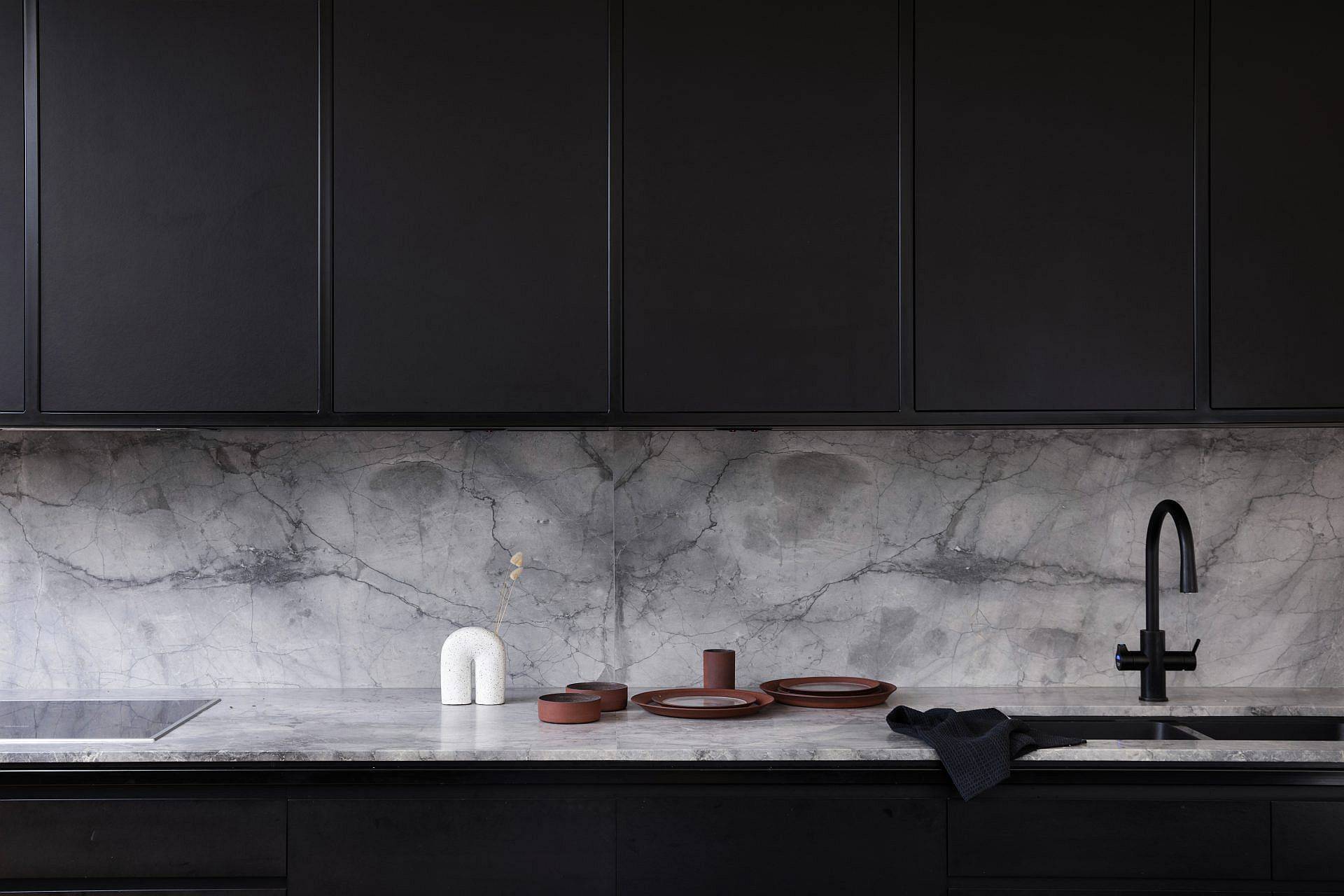 Modern kitchen in black and white with drak cabinets and marble backsplash and countertops