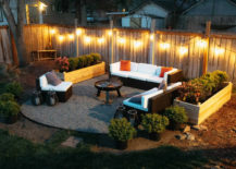 Outdoor firepit surrounded by white sofa with cushions and planters