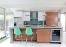 Three oranges on countertop with two mint green chairs