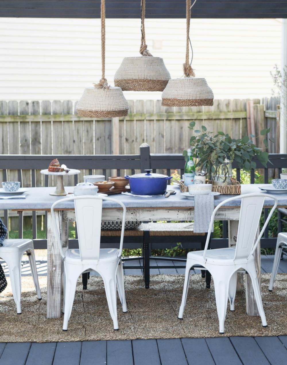 Three pendant lights made from baskets hanging above table on outside deck