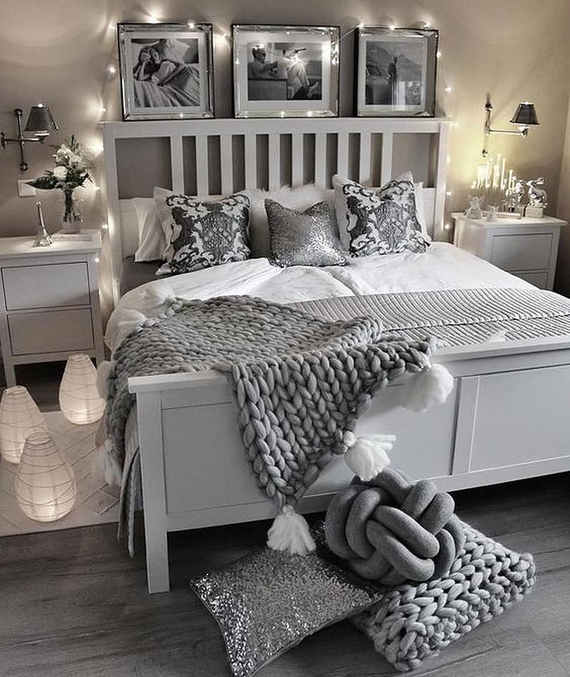 White and grey bed with string lights and pictures at the head