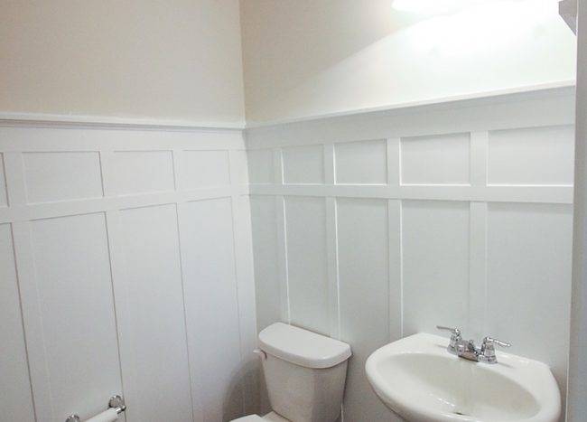 White toilet and white sink with white wall wainscoting