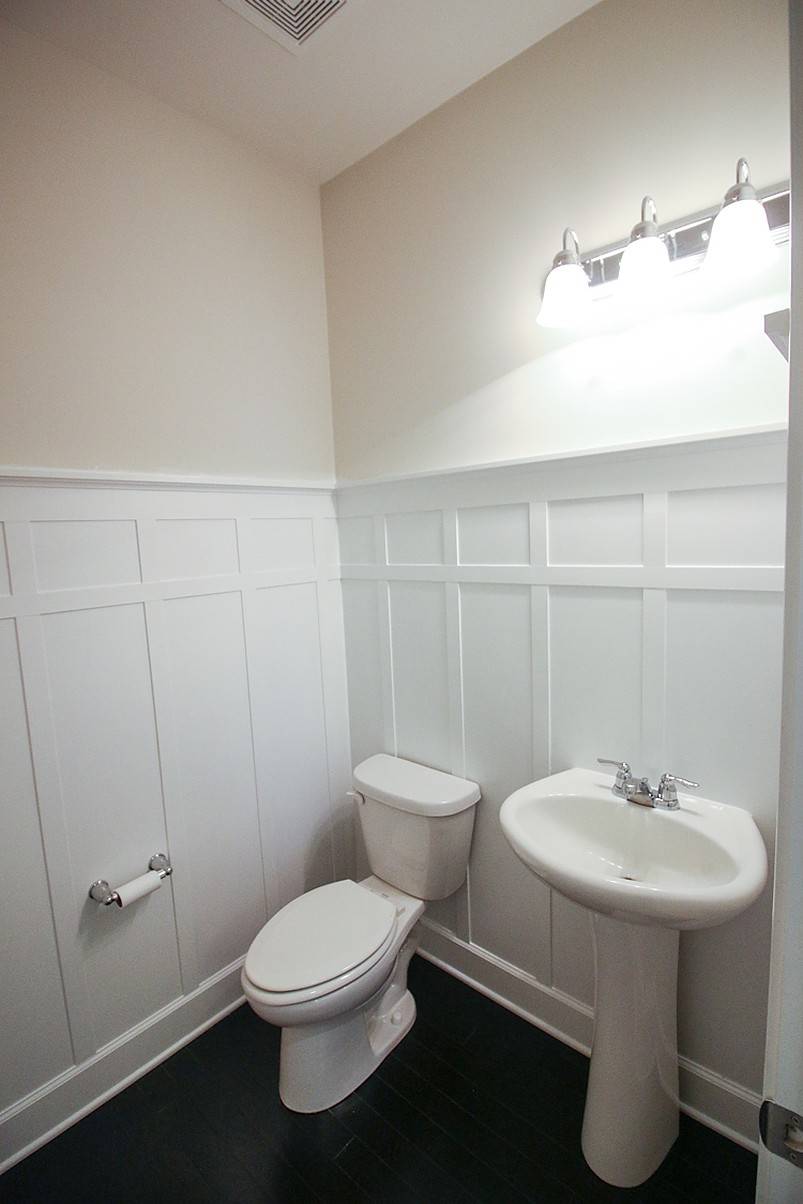 White toilet and white sink with white wall wainscoting