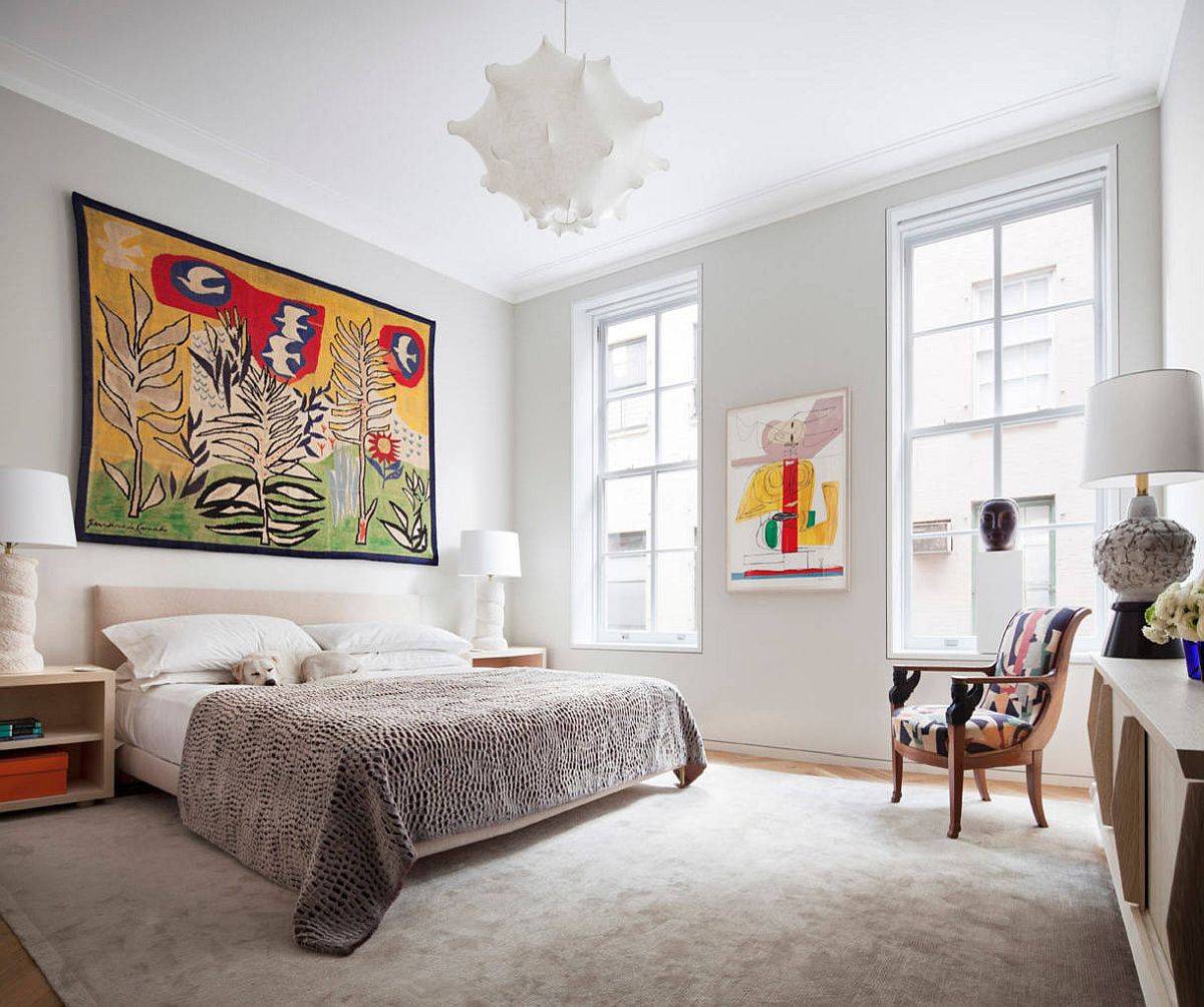 Beautiful and relaxing bedroom of the Tribeca home with white backdrop and eye-catching, colorful wall art