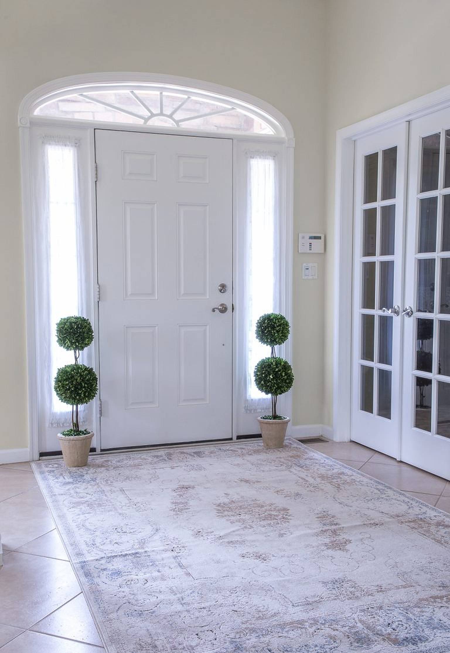 Elegant foyer with sculpted potted plants on each side of the door