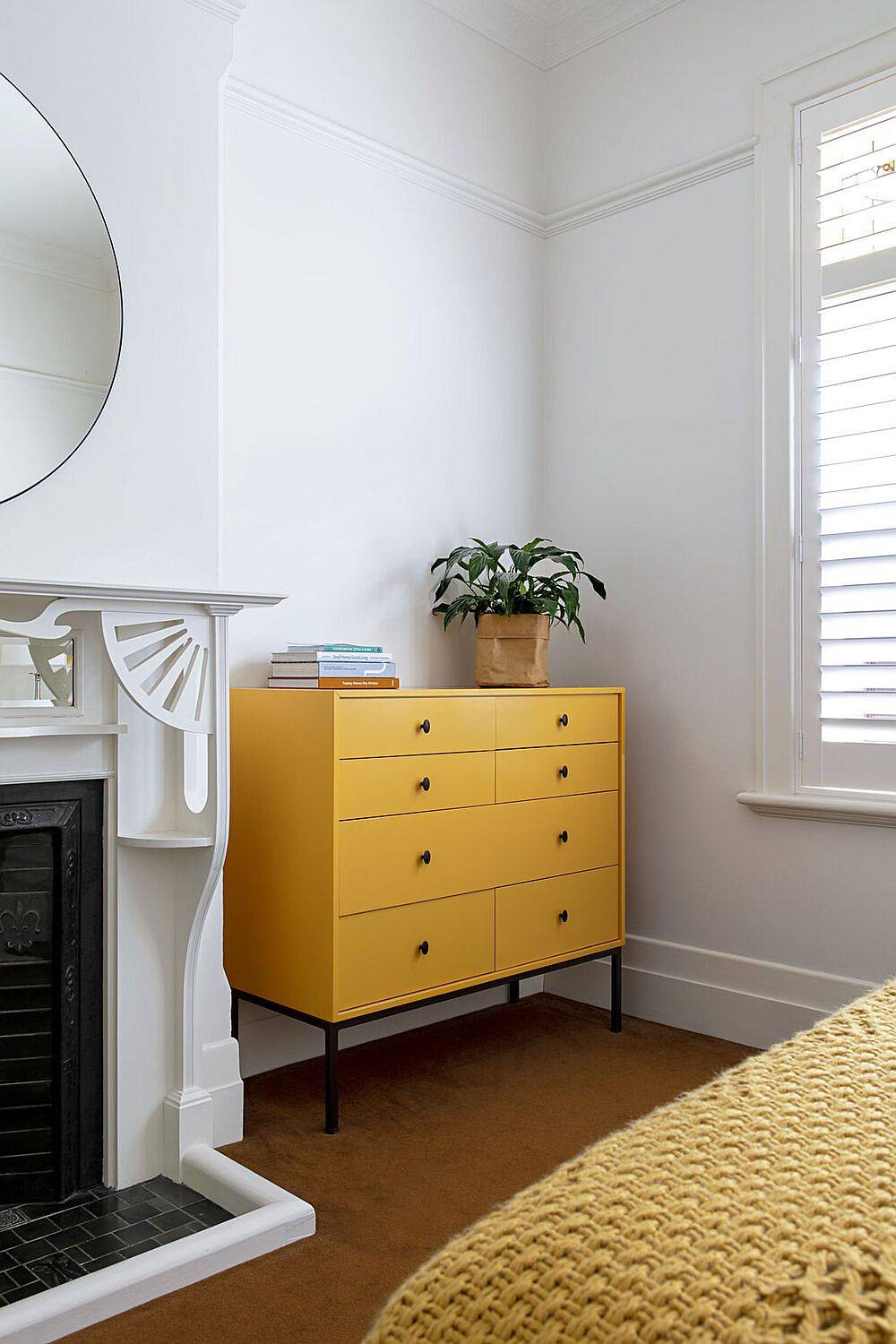 Gorgeous orange drawer in the bedroom adds color to the white transitional bedroom