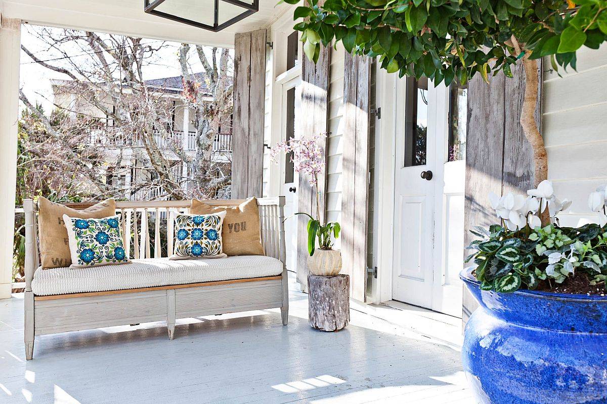 Lovely shabby chic porch in white with extended roof and a reclaimed wooden sofa for a relaxing evening