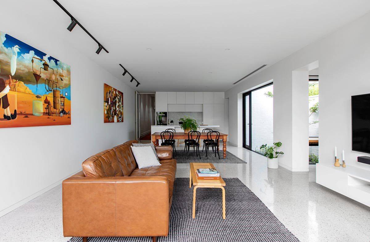 Open plan living area, dining space and kitchen in white with bright wall art and modern decor