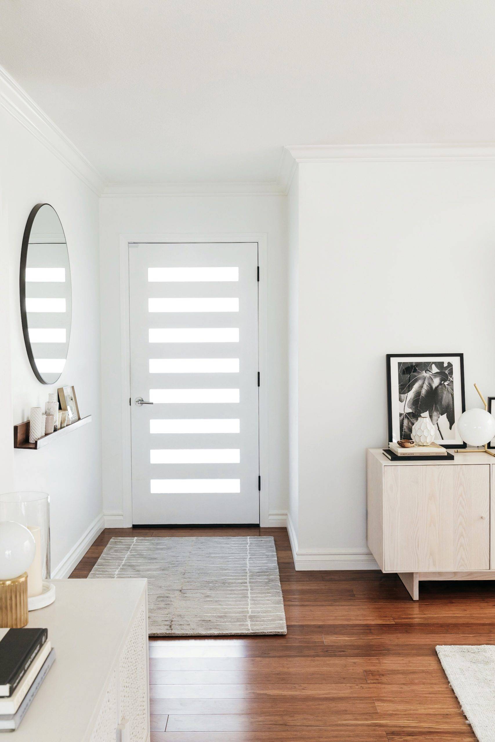 Round mirror hanging on wall beside white front door