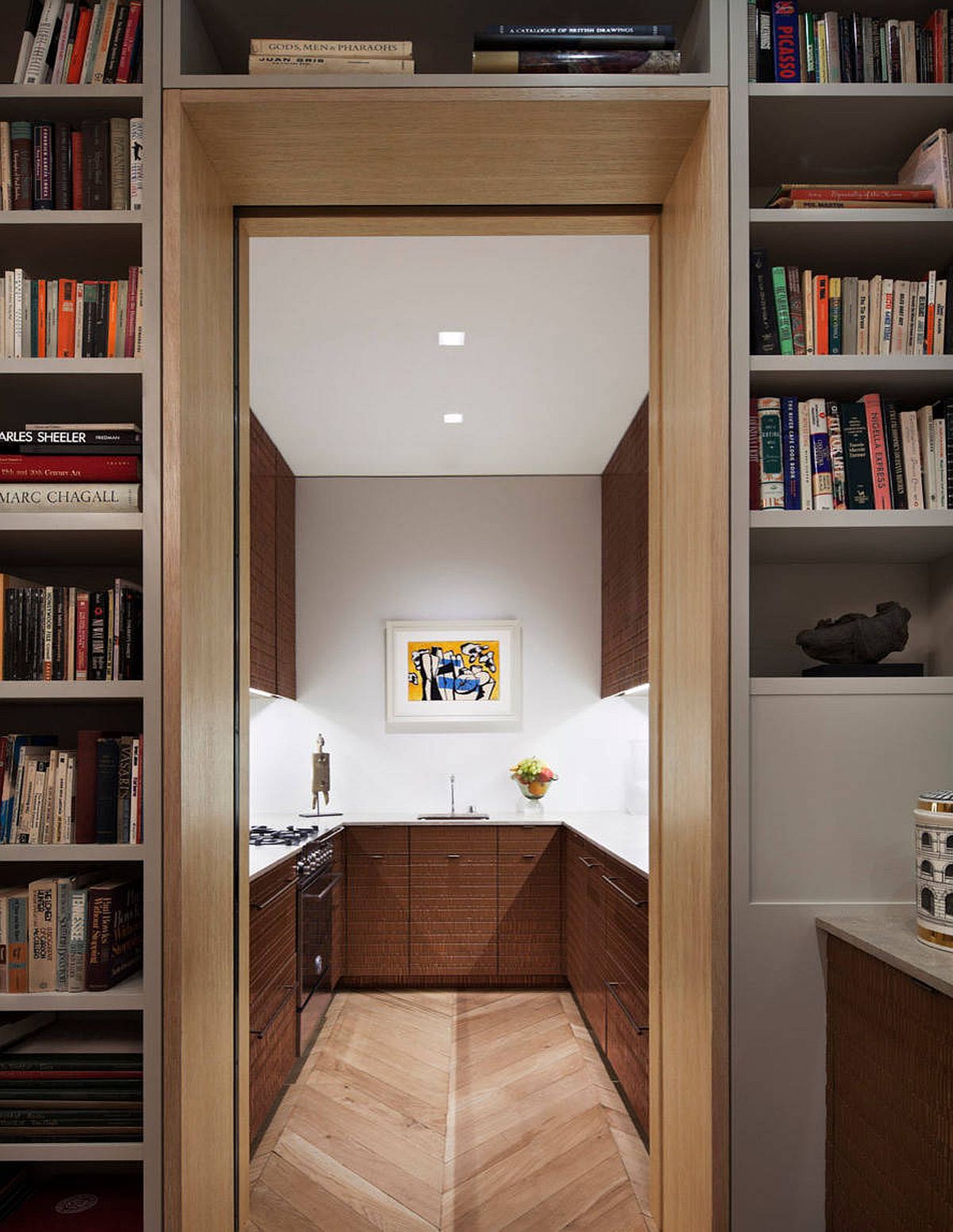 View of the modern kitchen with space-savvy design, chevron pattern wood floor and oak cabinets