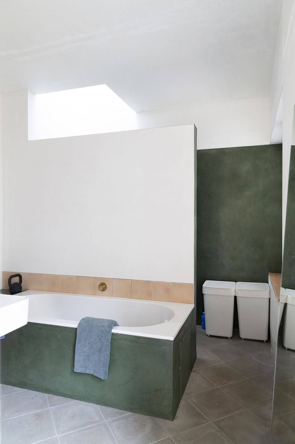 Contemporary bathroom in neutral hues with skylight and dark green accents