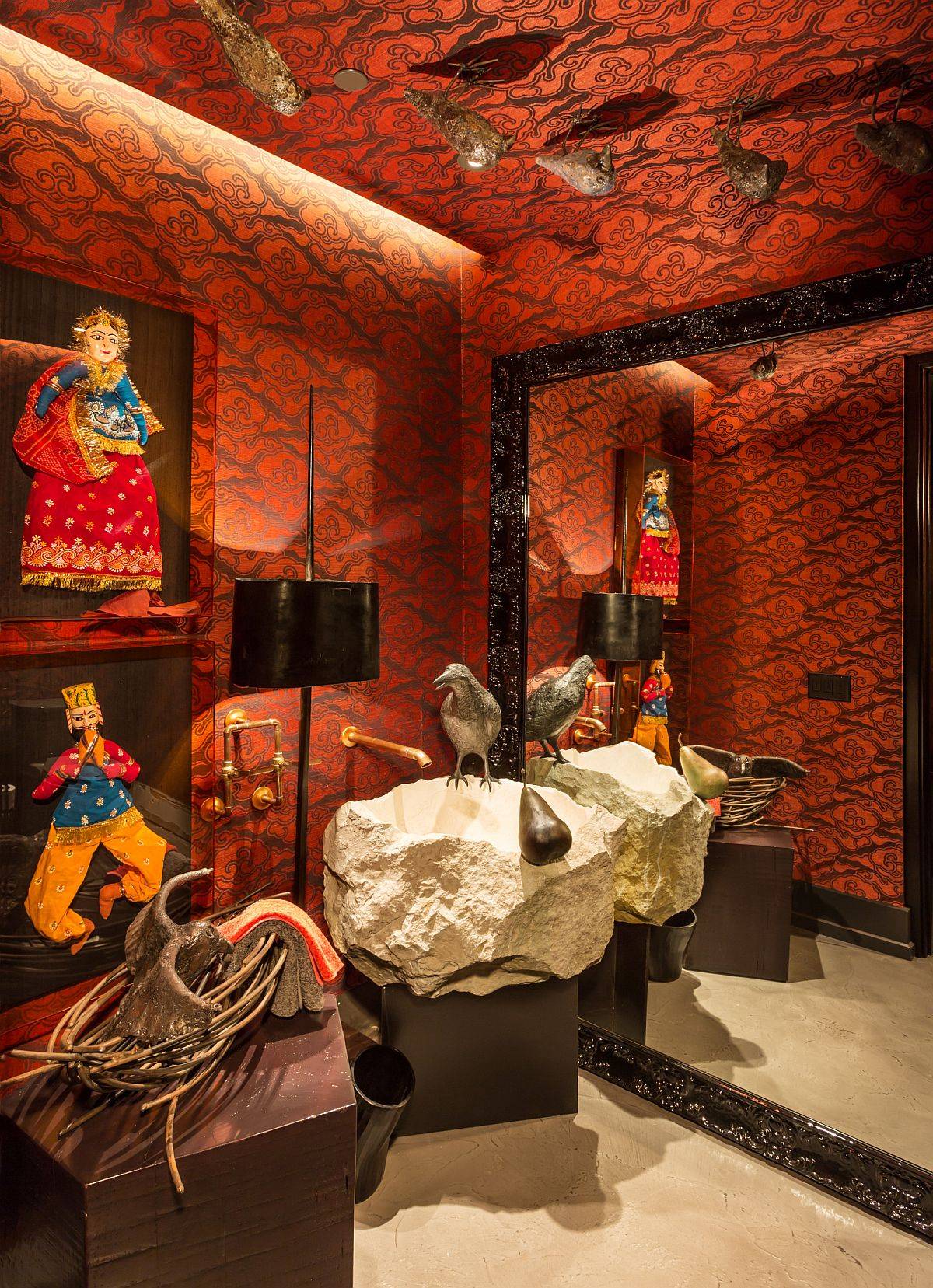 Eye-catching orange wallapaper, custom stone sink and puppet artwork with Indian theme shape a truly unique eclectic powder room