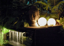 glowing orb lantern next to head sculpture and water feature
