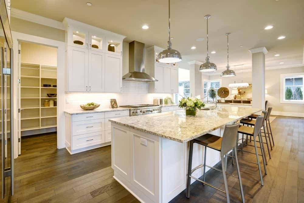 bright white kitchen with granite countertops and entrance to walk in pantry