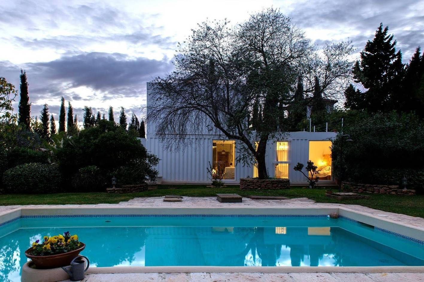 white two story container home at night with pool