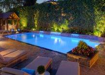 in ground pool at night lit up with stone patio and water feature