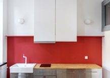 red wall in kitchen with stainless steel appliances and white cabinets