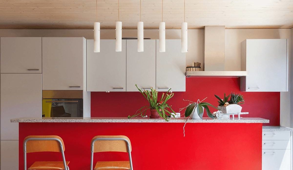 bright red kitchen island with white upper cabinets and hanging candle lights