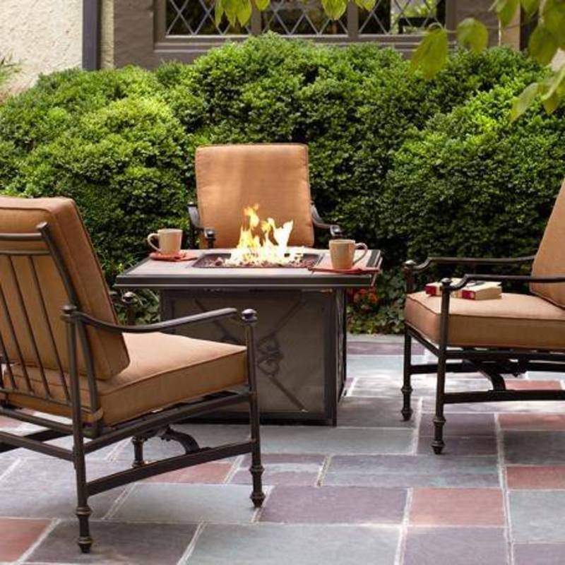 lit firepit with beige chairs surrounding on patio