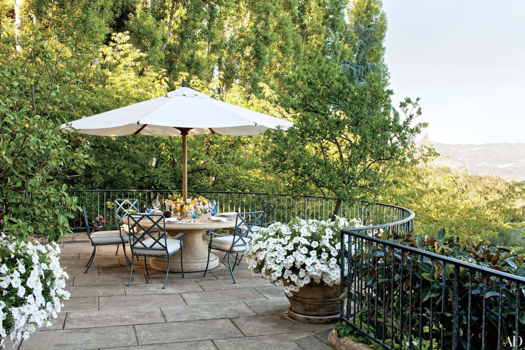 seats on a balcony shaded by an outdoor umbrella