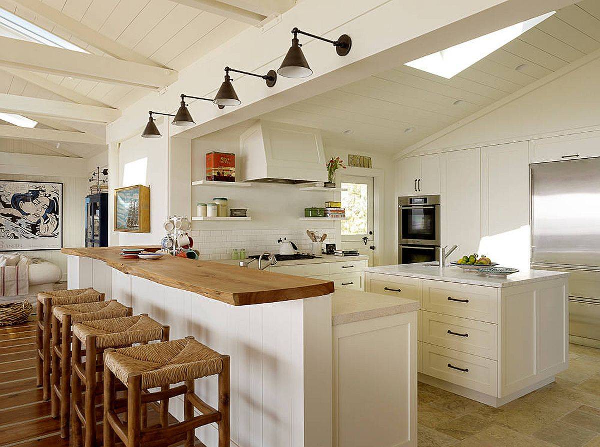 Coastal style kitchen with sconce lighting, skylight, breakfast bar and an island in white