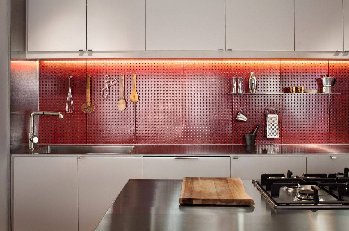 Custom pegboard backsplash in the kitchen also adds a lovely dash of bright red to the contemporary space