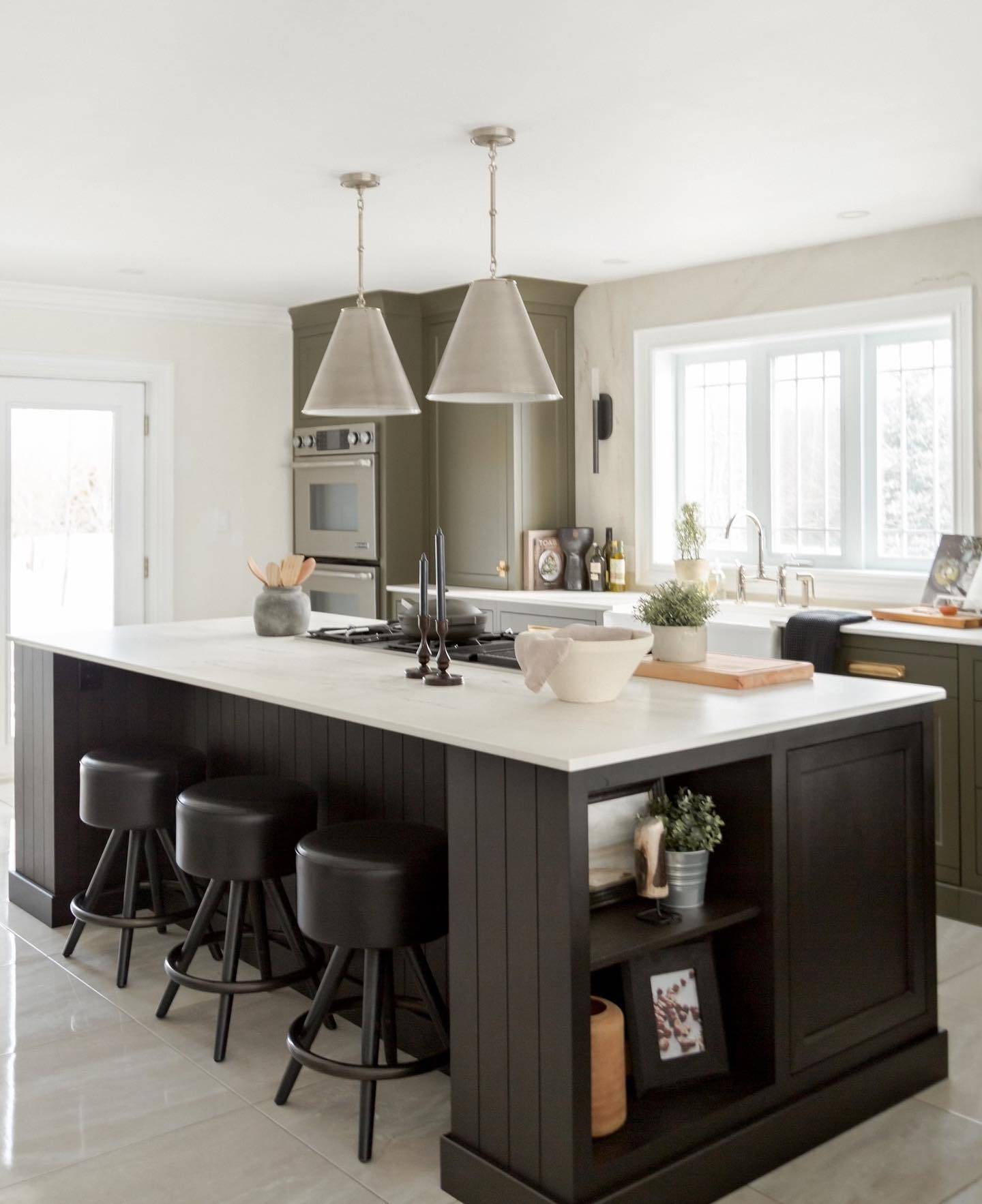 green kitchen cupboards with black island hanging pendants