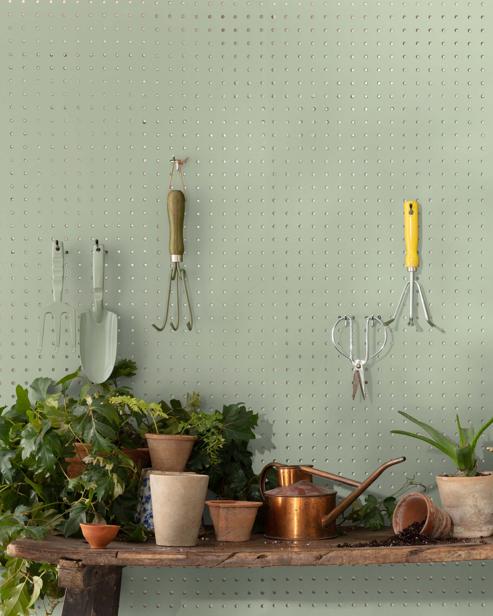 green paint pegboard wall with gardening equipment terracotta pots