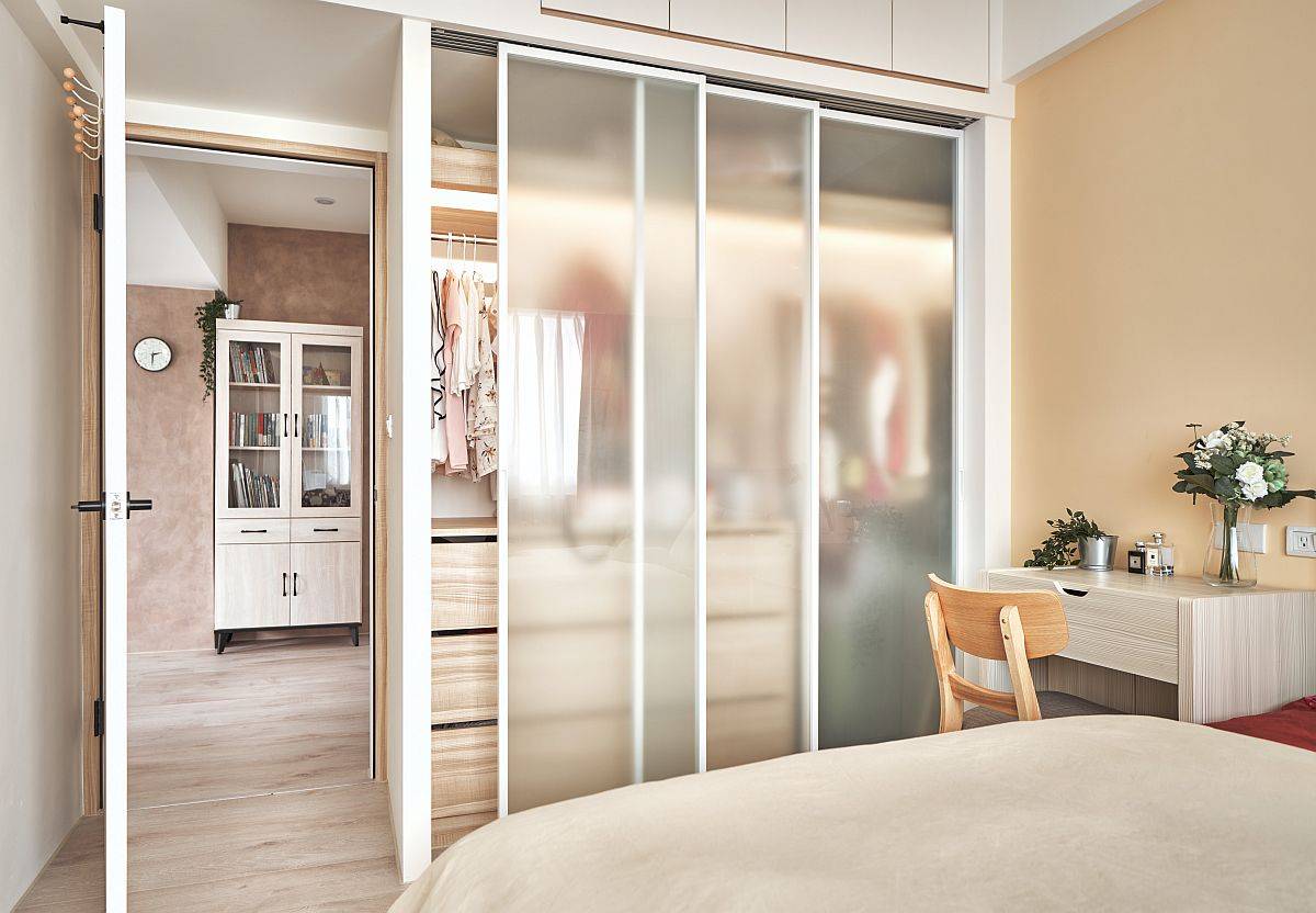 Modern space-savvy bedroom idea with custom wardrobe that features frosted glass doors