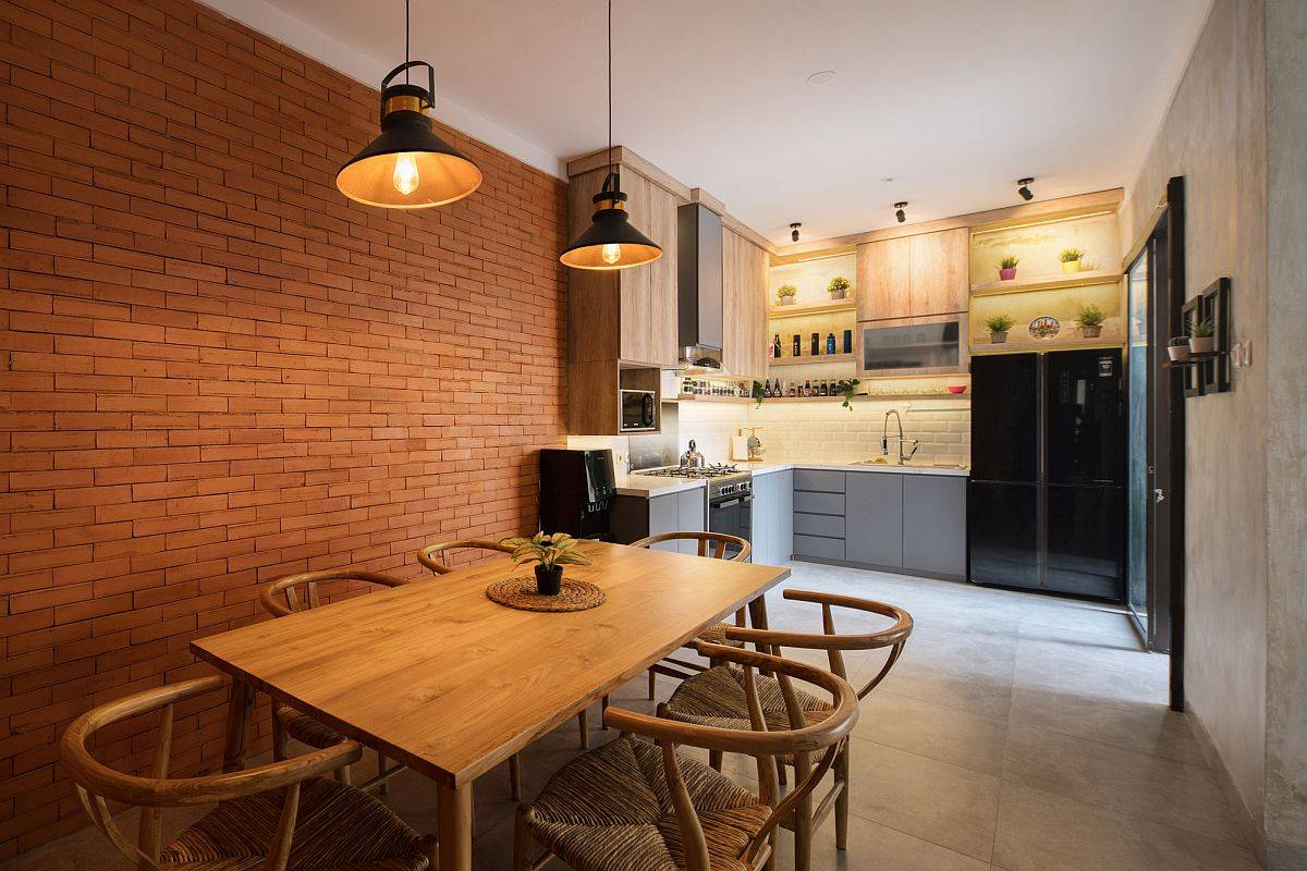 Small kitchen and dining area of the lovely Indonesian home withe xposed brick walls and concrete finishes