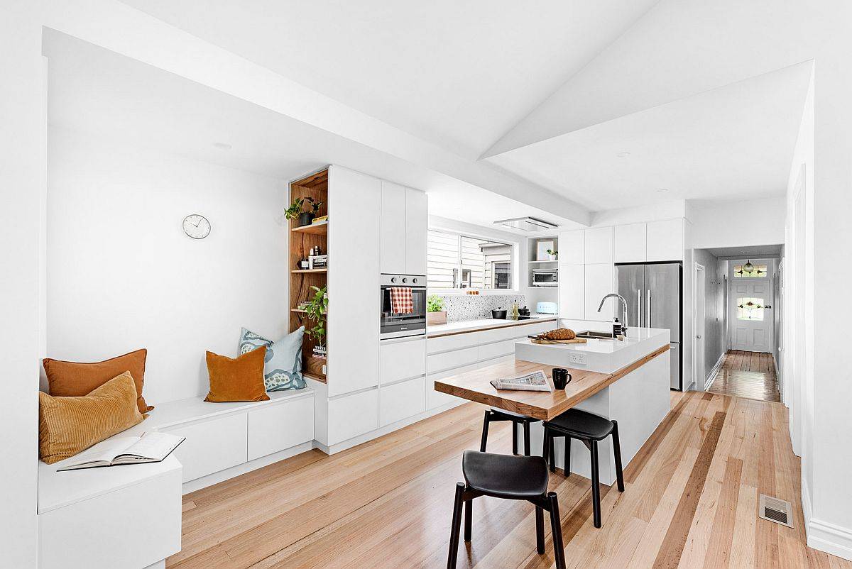 Smart and modern extension of the kitchen island is a wooden breakfast bar that brings visual contrast to the space