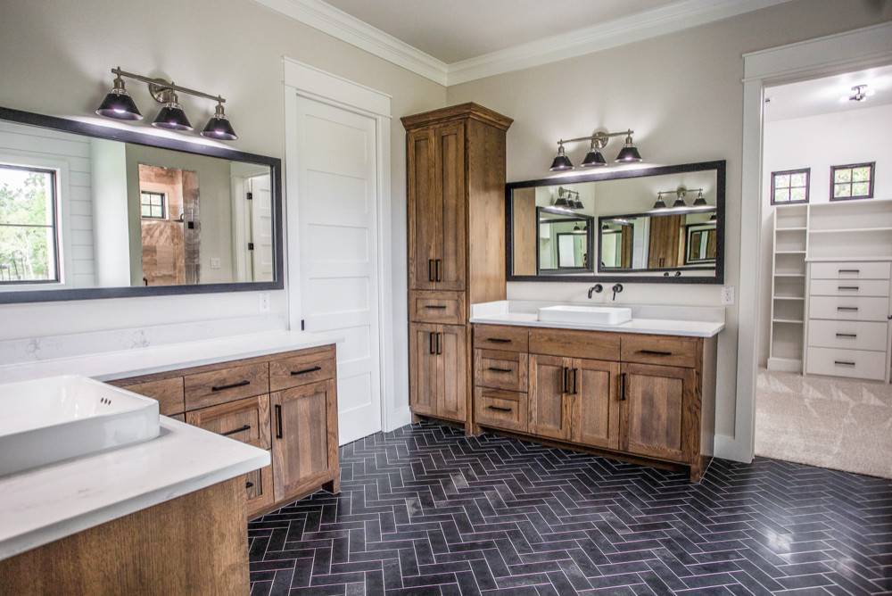 Spacious farmhouse style bathroom in white and wood with dark tiled floor in herringbone pattern