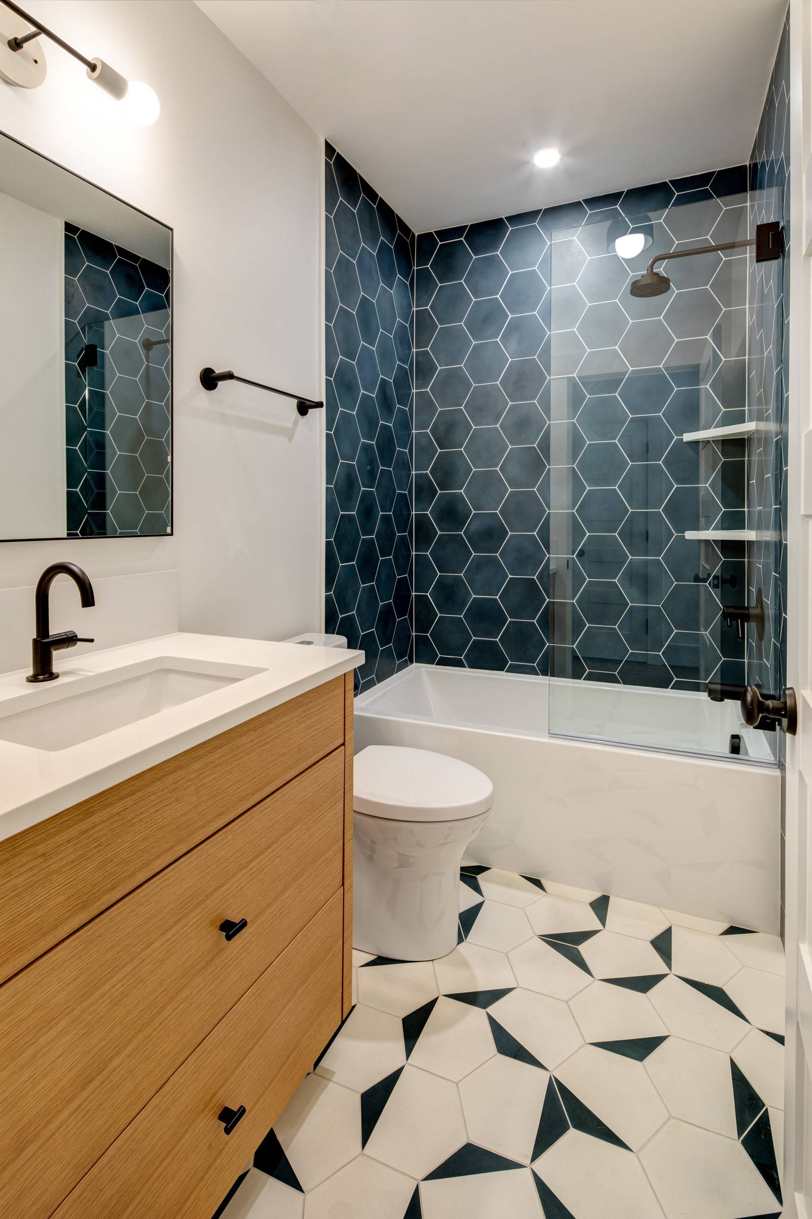 Two different colored hexagonal styles adorn both the walls and the floor of this contemporary bathroom