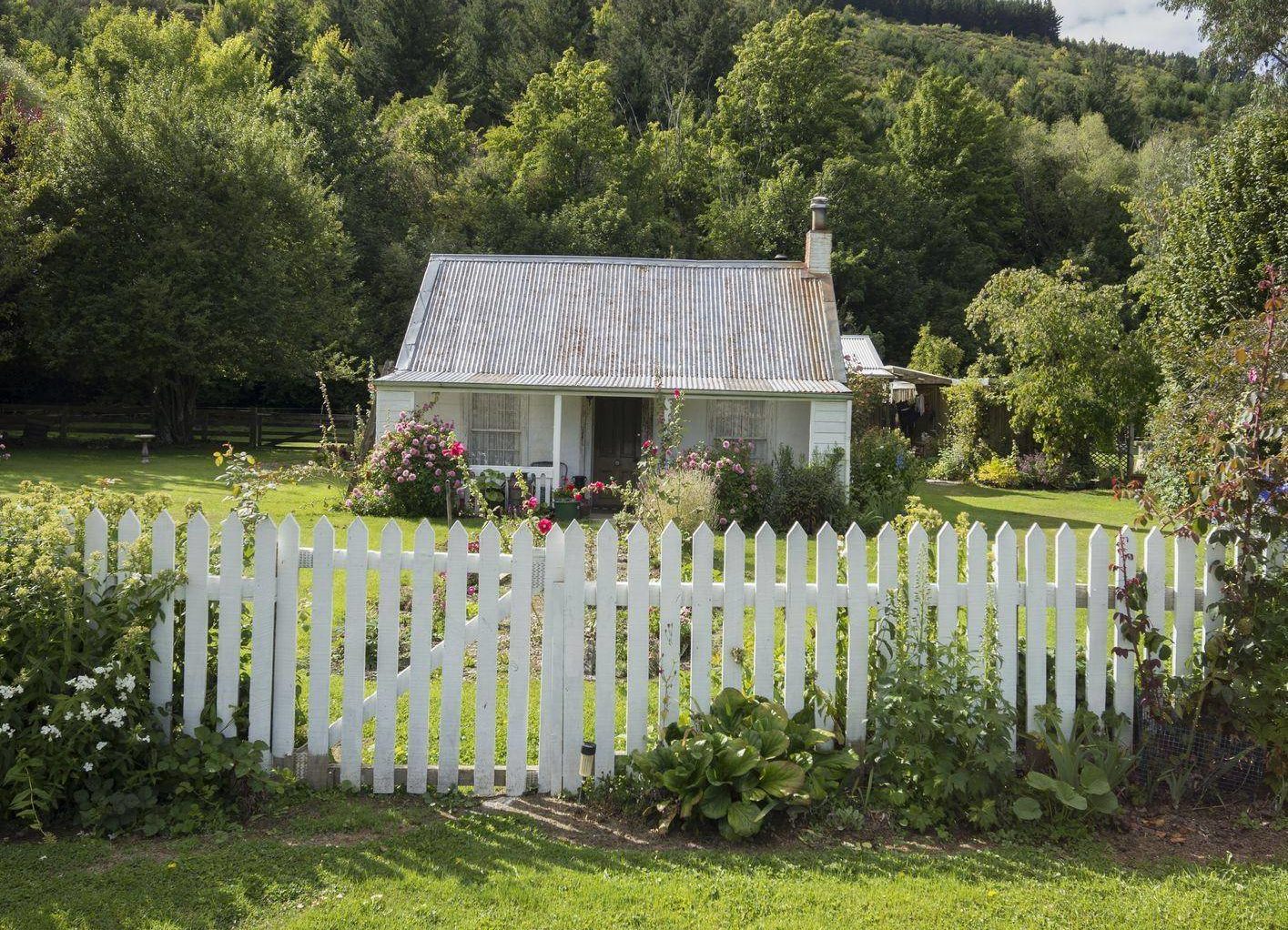 white picket fence in front of cottage