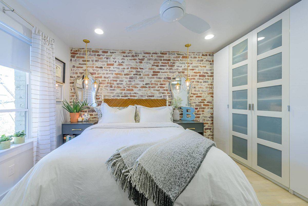 Brick wall and custom headboard steal the spotlight in thsi cozy white bedroom