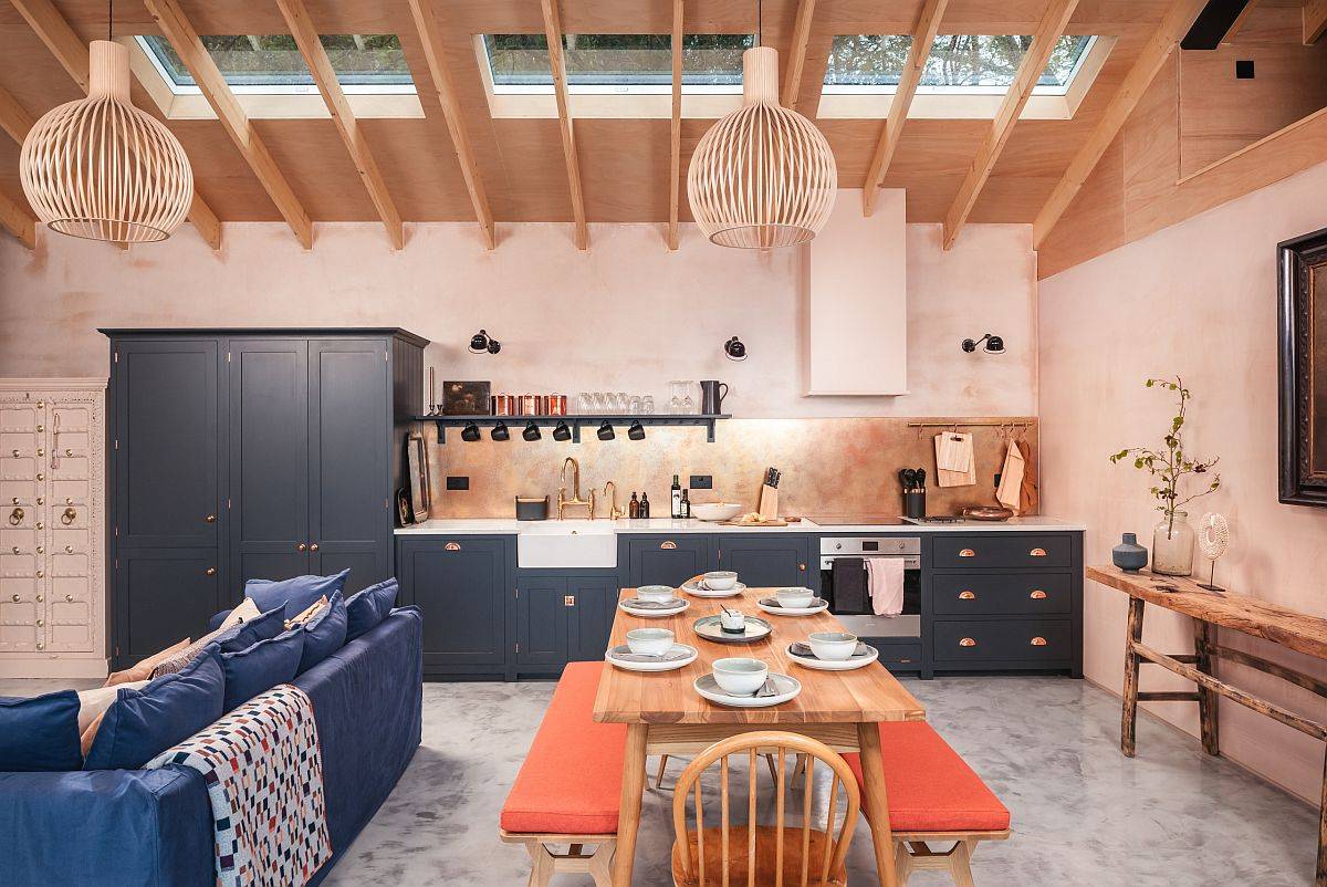 Eye-catching Scandinavian style kitchen with light pink walls brings orange to the setting using twin benches at the dining table