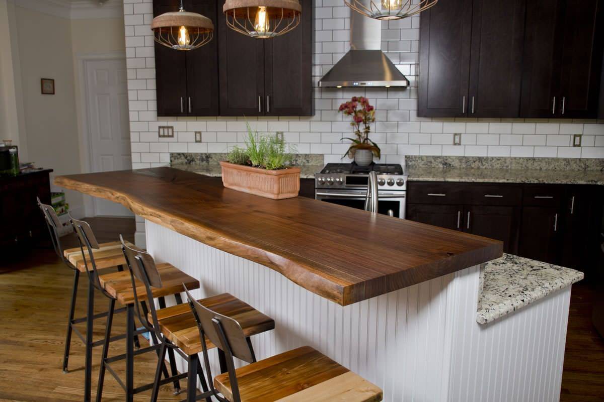 Polished black walnut tree countertop serves as the breakfast bar in this small industrial kitchen with a convenient island