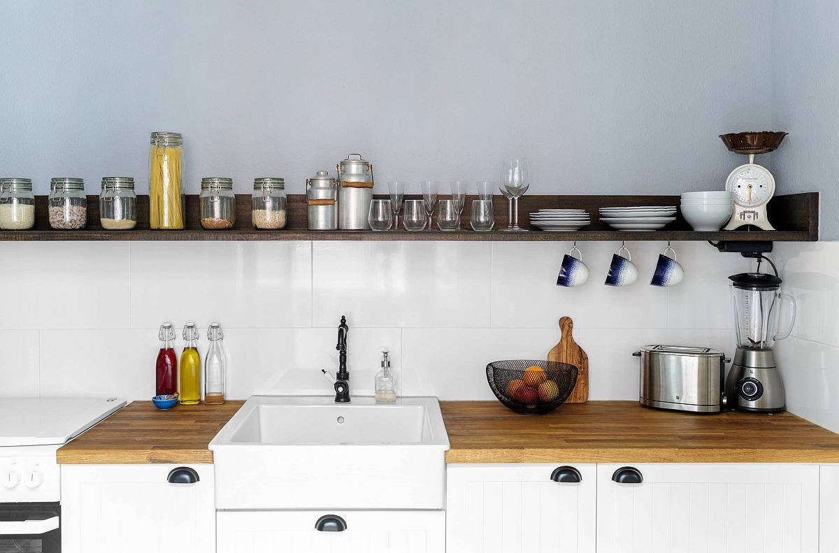 Slim floating shelf in wood provides open storage option in the one-wall kitchen