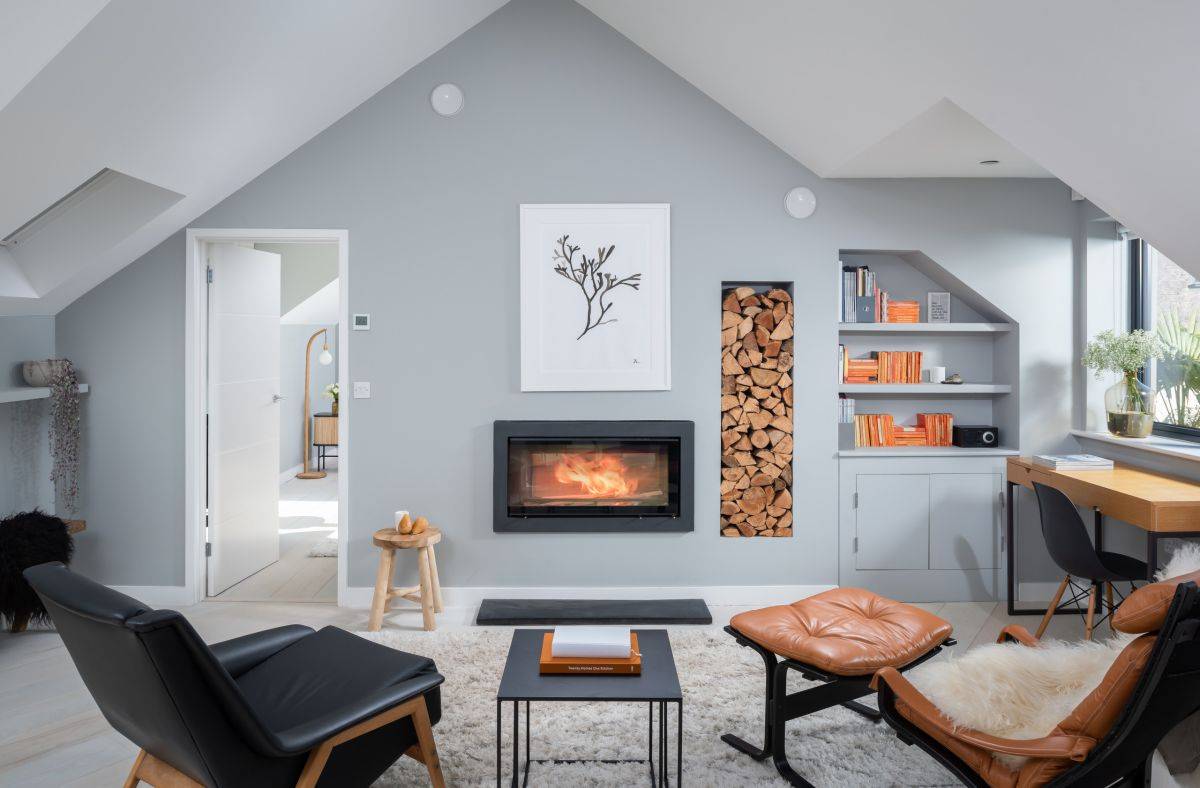 Gorgeous modern beach style living room in gray with a lovely fireplace and stacked firewood next to it