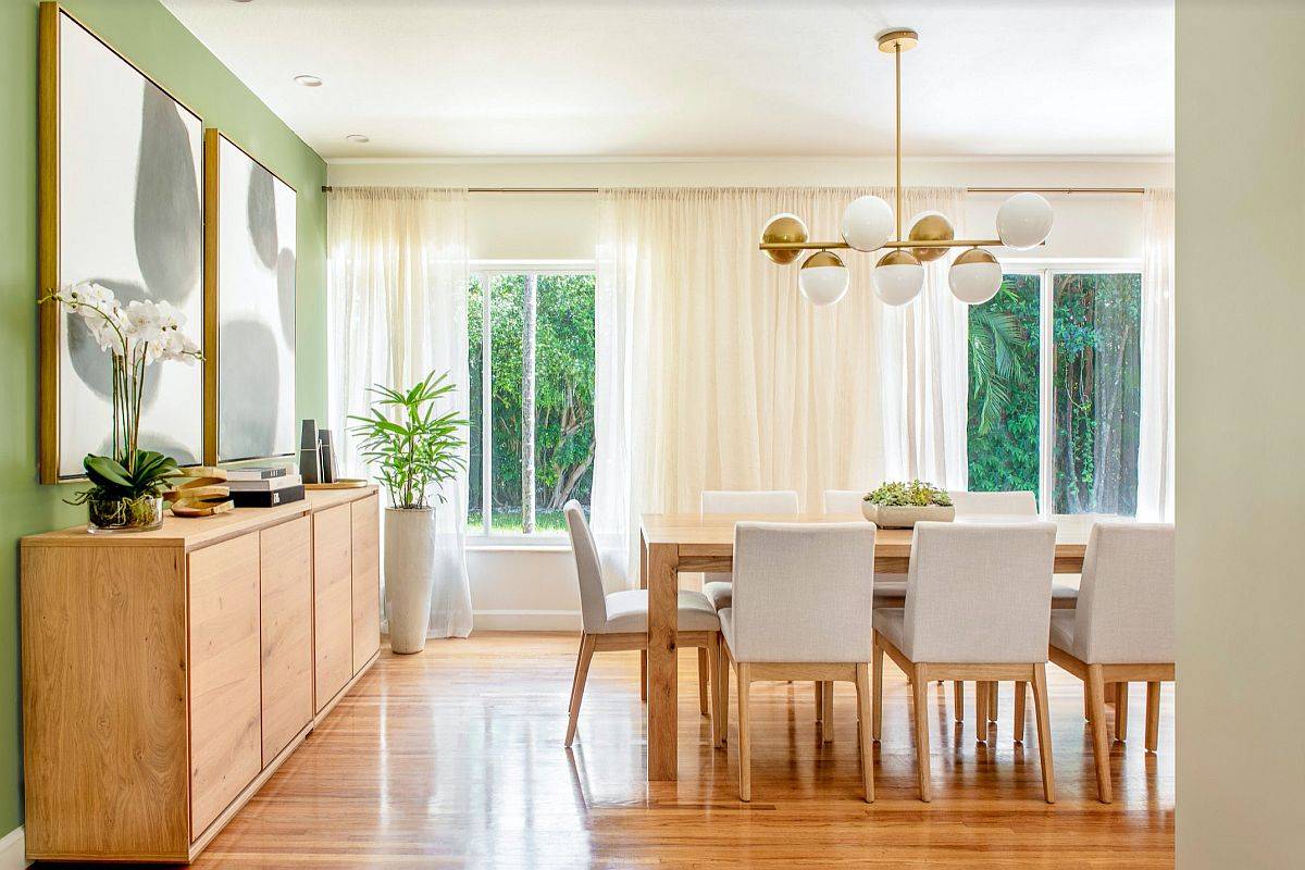 Modern dining room with trendy green accent wall and lovely pieces of wall art in black and white