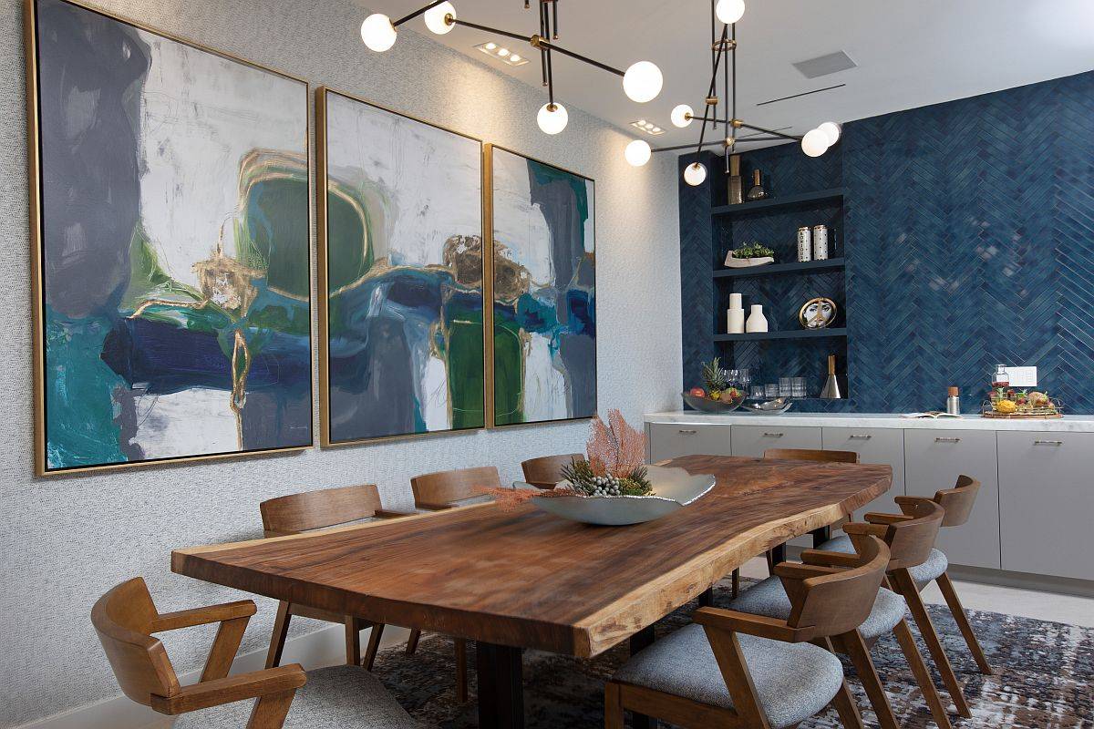 Striking wall art in this dining room steals the spotlight despite the lovely serving area, natural wooden table and lovely blue background