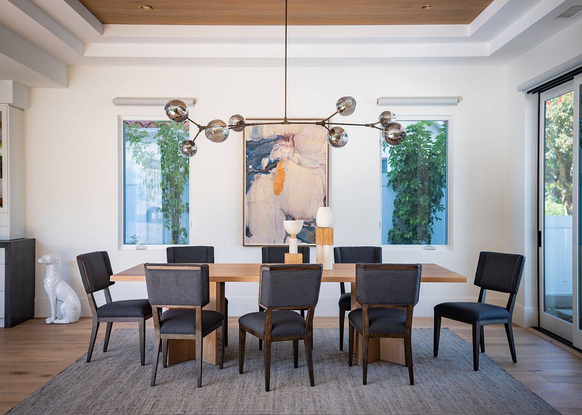 Wall art piece in this dining room is placed smartly between the two windows to create visual symmetry