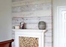 Whitewash wood accent wall with a fireplace filled with quarter logs.